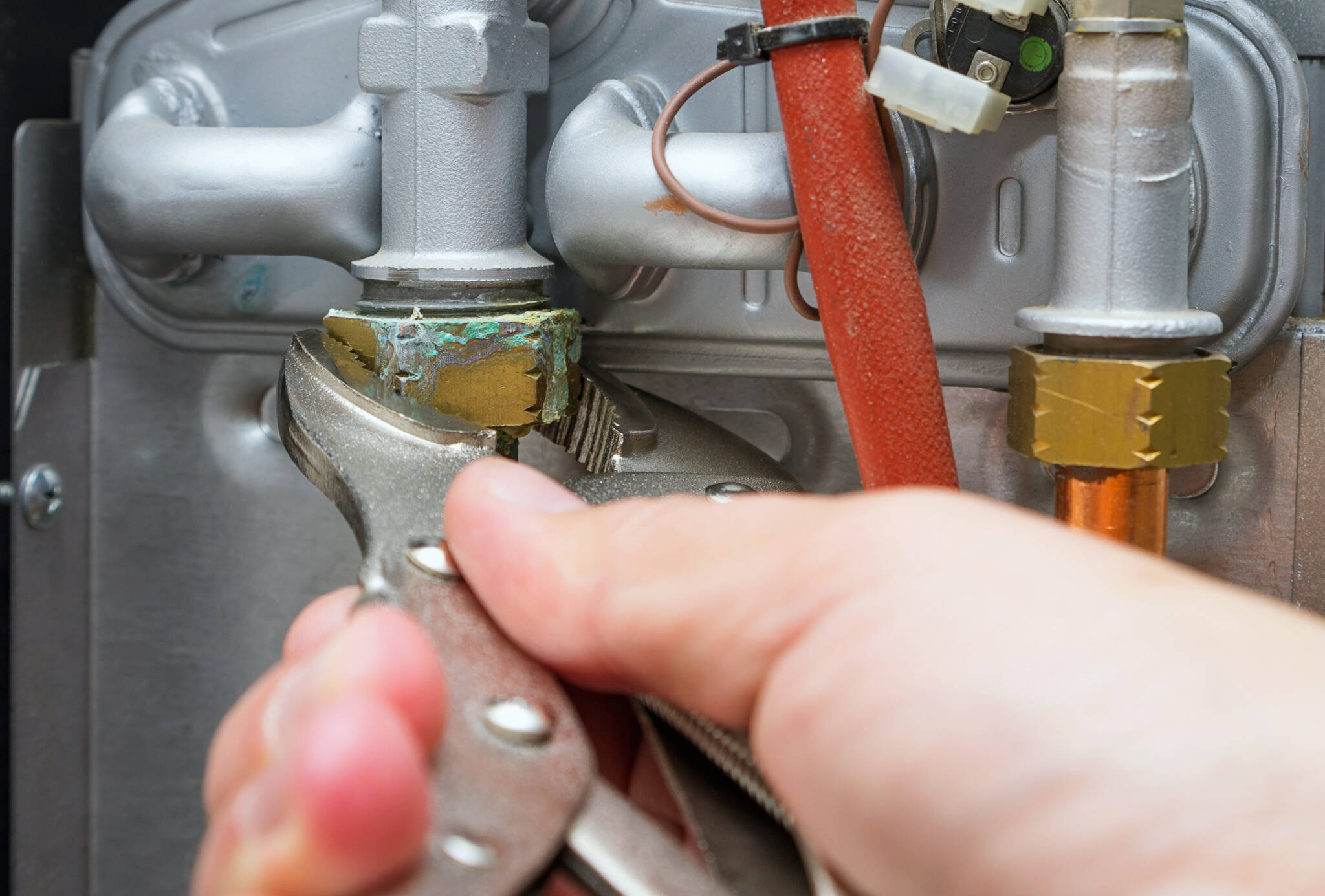 Servicing A Heating Home System.technician With Wrench Repairs Leaked Hot Water Pipe In Gas Boiler. Close Up, Selective Focus. Servicing A Heating Home System.technician With Wrench Repairs Leaked Hot Water Pipe In Gas Boiler. Close Up, Selective Focus.
